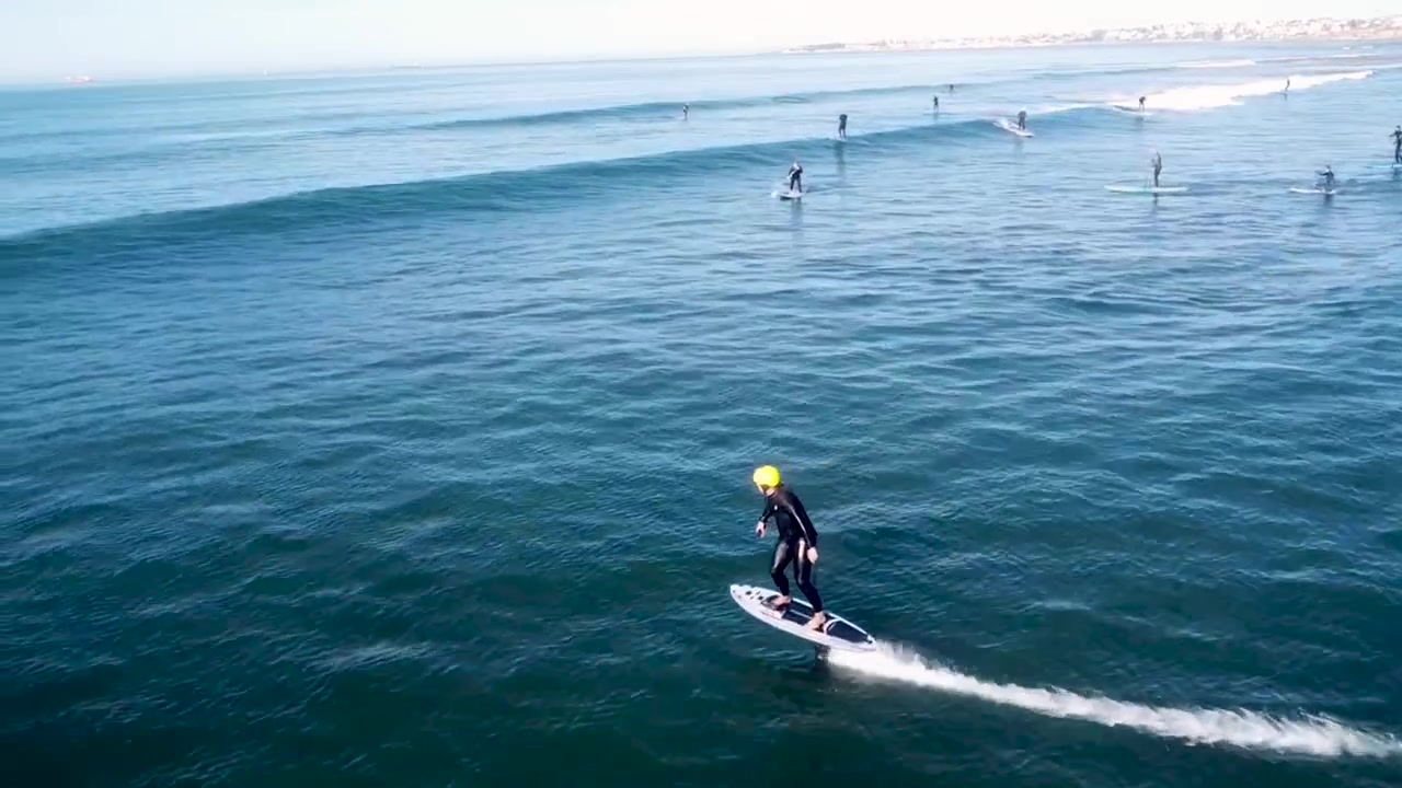 Vista di una persona su un jetsurf in mare con un gruppo sullo sfondo. Di giorno