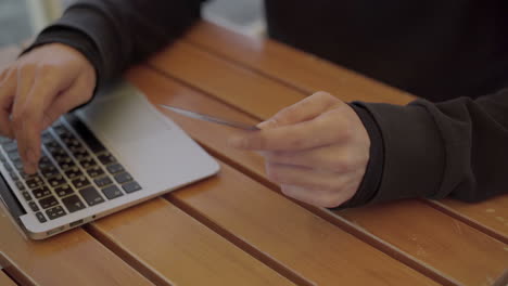 Man-holding-credit-card-and-using-laptop