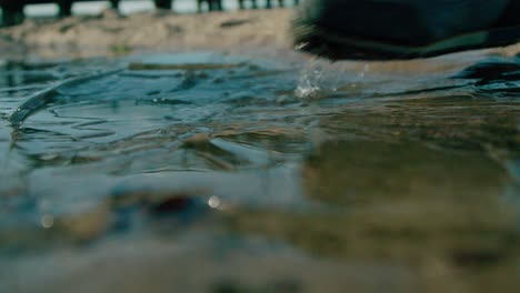 a foot of a man stepping on a water with crack ice - close up shot