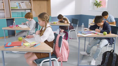 grupo de alumnos de primaria multiétnicos escribiendo en su cuaderno durante la clase de inglés 1