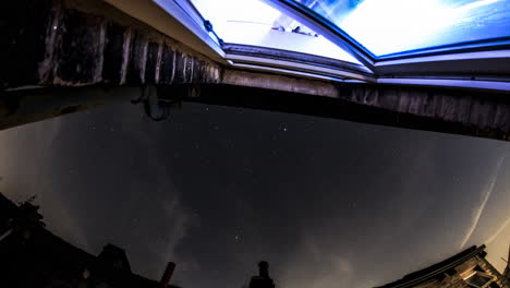 timelpase de observación de estrellas de un cielo nocturno muy ocupado tomado desde un alféizar con una ventana parpadeante en el fondo de la toma