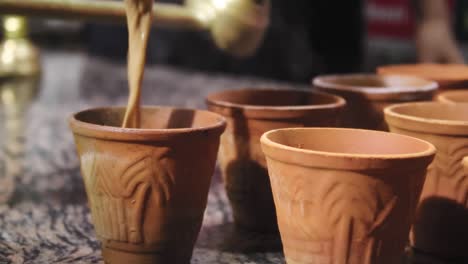 close up of hot indian tandoori chai being poured into clay cup. follow shot