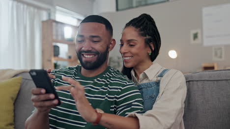 happy couple with phone on sofa in living room