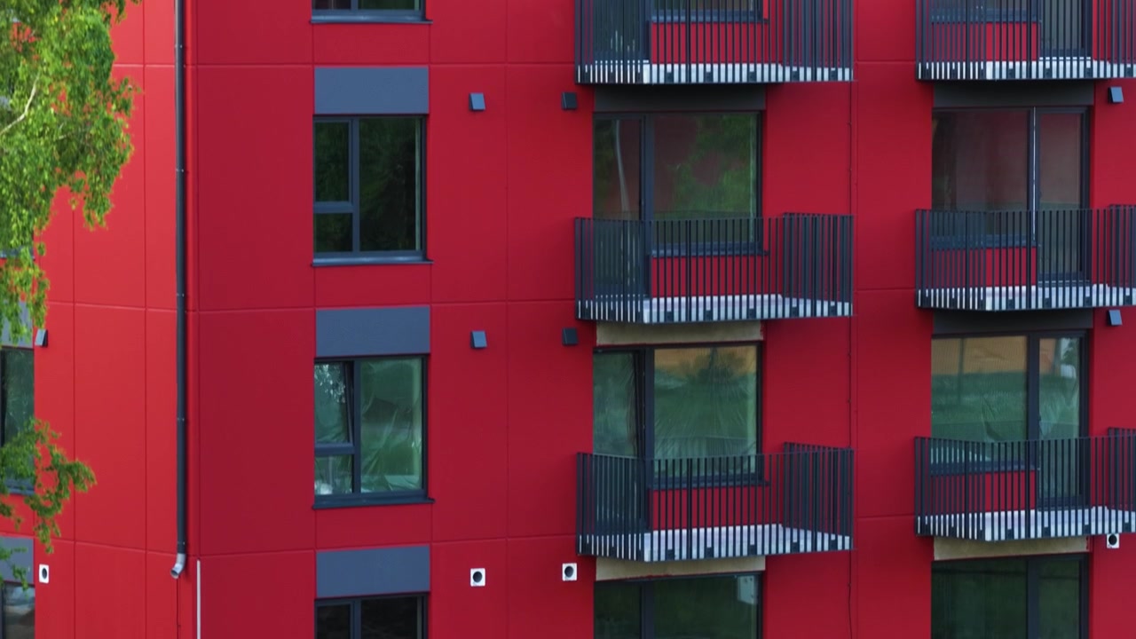 Contemporary residential property featuring a striking red facade and black balconies