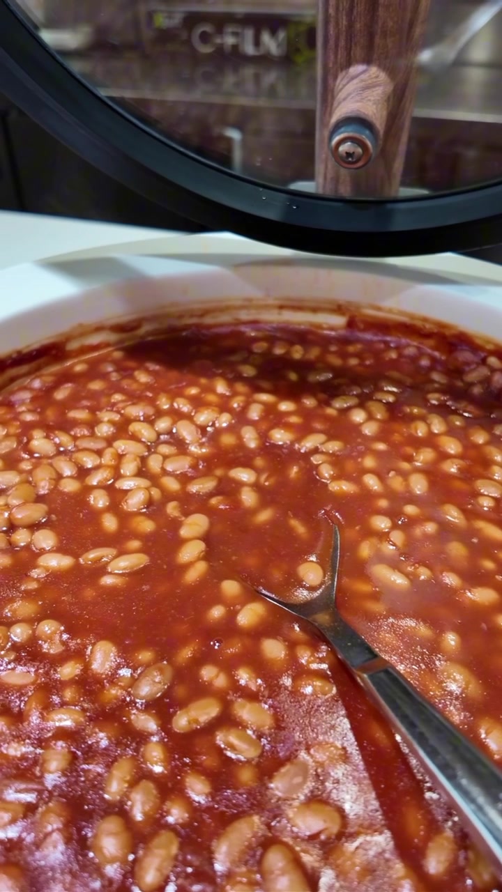 Fagioli al forno caldi che sobbollono in un piatto da portata.