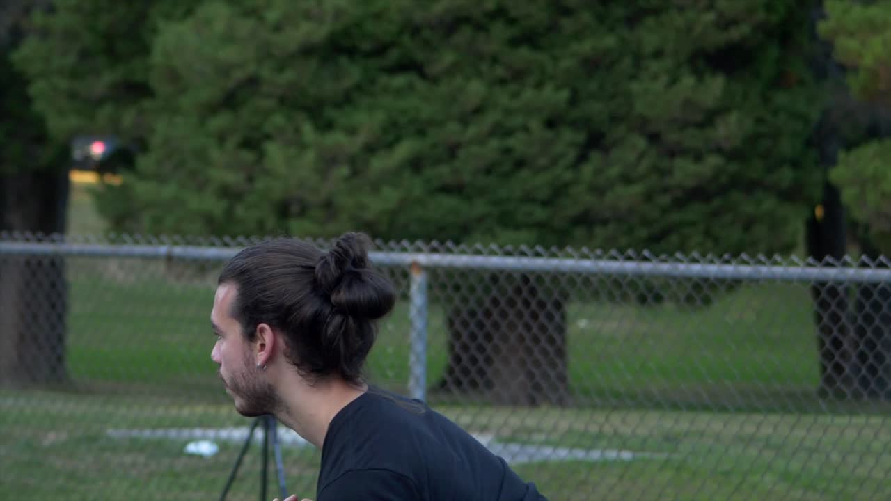 Behind a Long haired Male Serving a Tennis Ball to His Opponent at Hasting Community Park