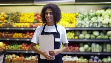 retrato de una empleada afroamericana de pie con una tableta en un supermercado y sonriendo