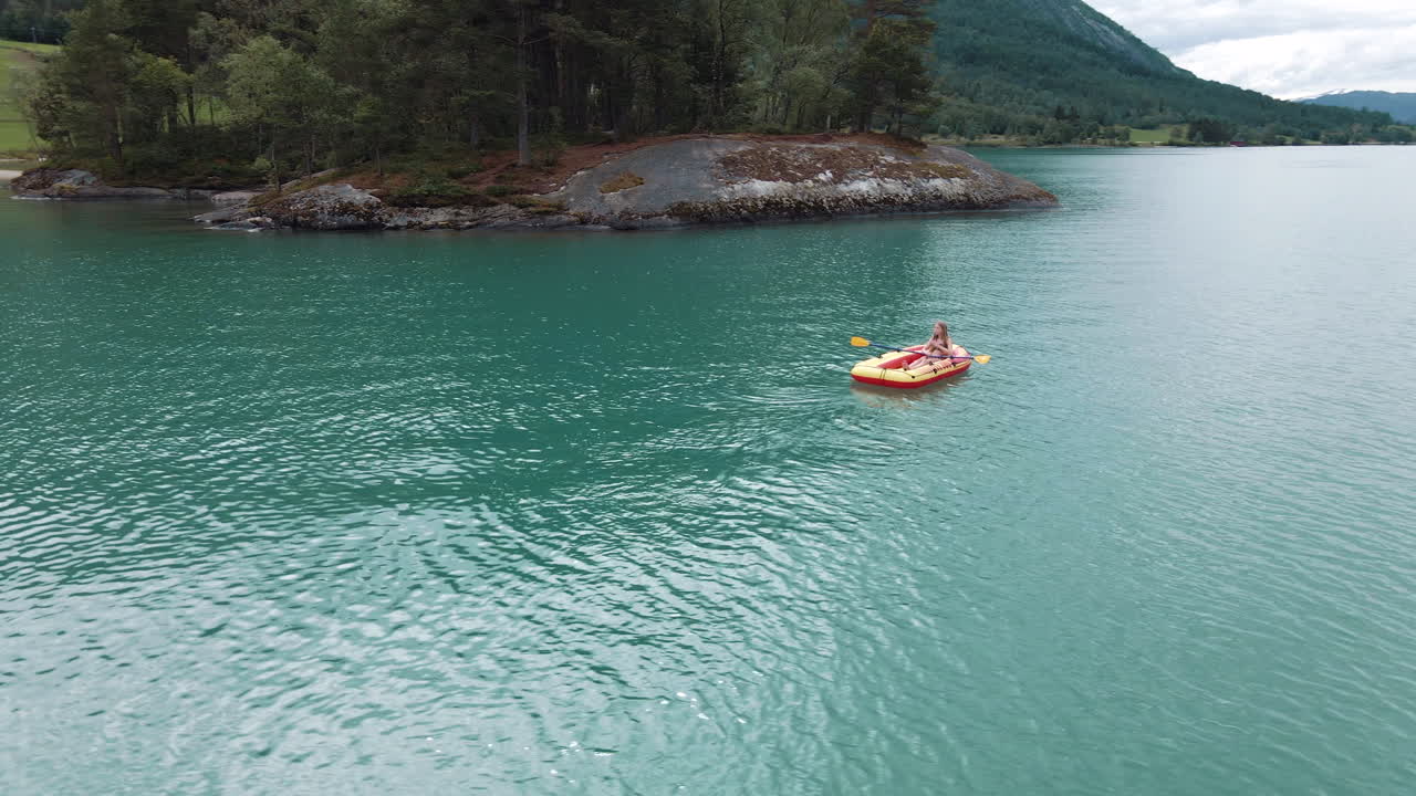 dando vueltas alrededor de una niña remando un bote de plástico amarillo en un lago
