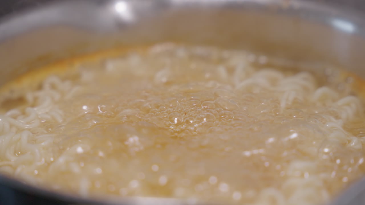 Slow motion, close up of instant noodles cooking in a pot