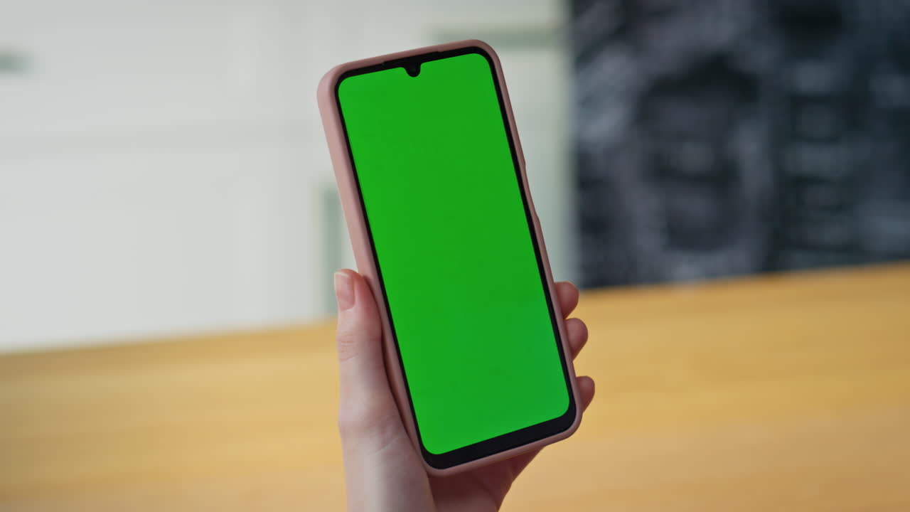 Lady hand holding chroma key cellphone at home closeup. Woman green screen phone