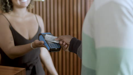 closeup of black man paying with credit card at terminal.