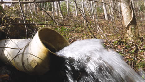 an open drainage pipe flowing water at a forest in georgia