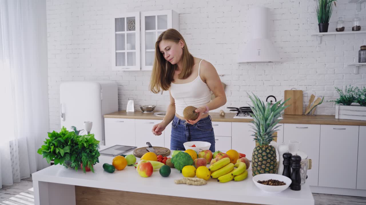 Woman with coconut in kitchen. Happy young woman in kitchen with coconut in hand