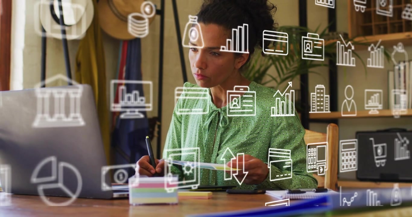 Businesswoman picking up document and taking notes referencing laptop with finance icons appearing