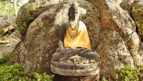 estatua de buda con pequeñas ofrendas a su alrededor en la estupa de red feather lakes, co.