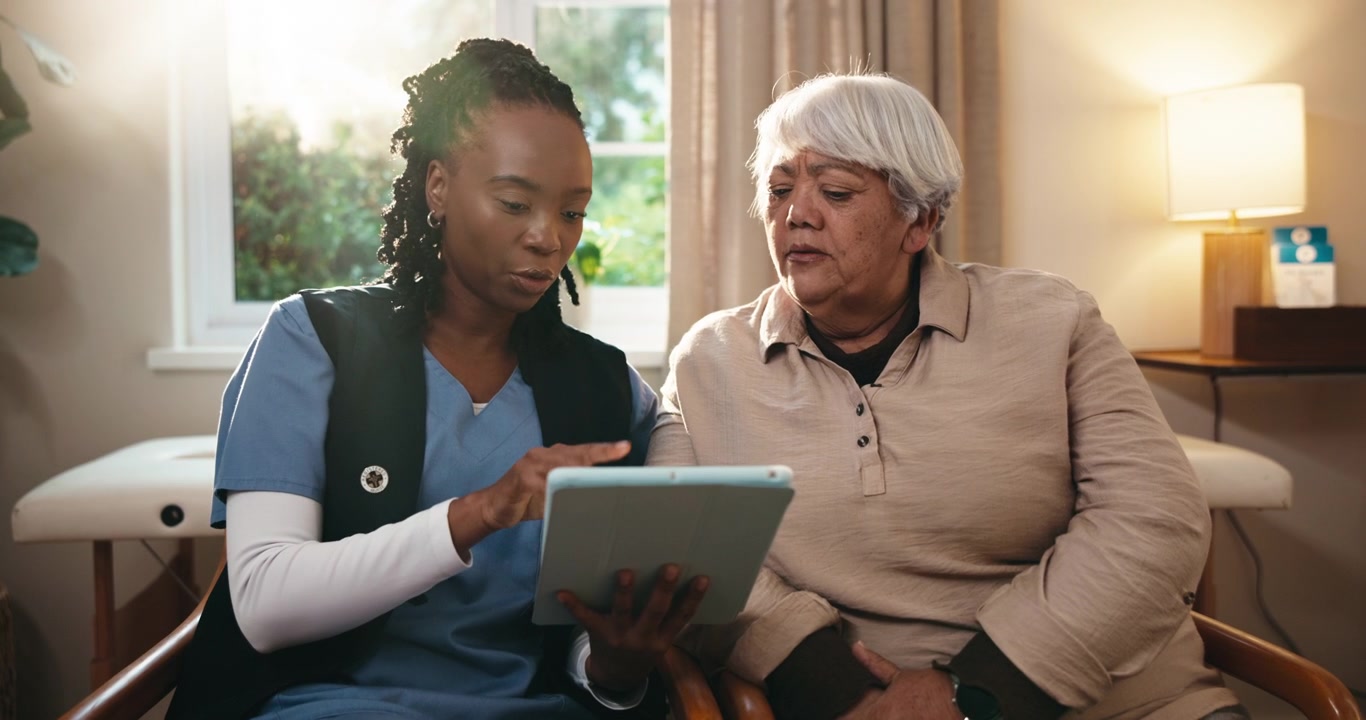 Caregiver Explaining Medical Information to Senior Woman on Tablet