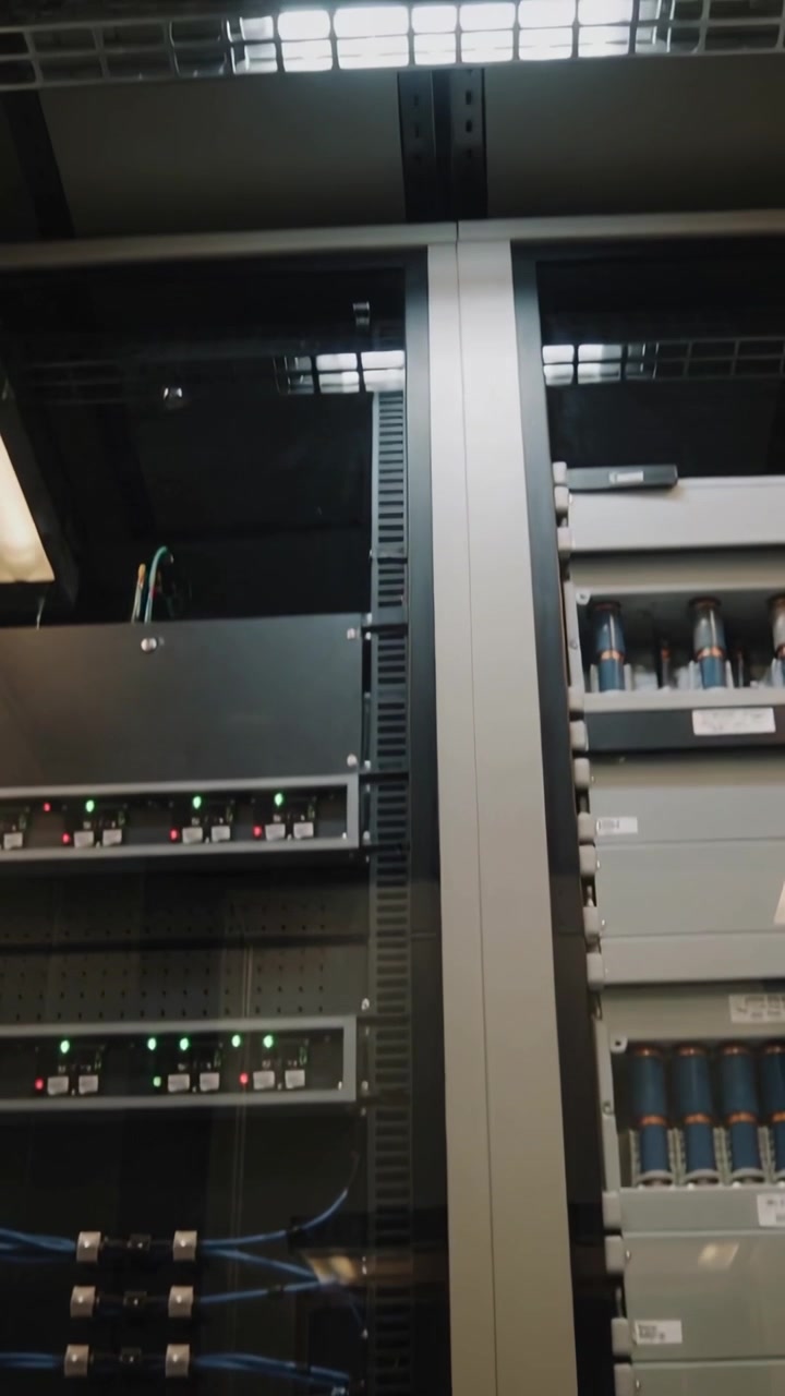 Vertical video: Tilting camera revealing two racks in telco room, for LEDs and blue cable check