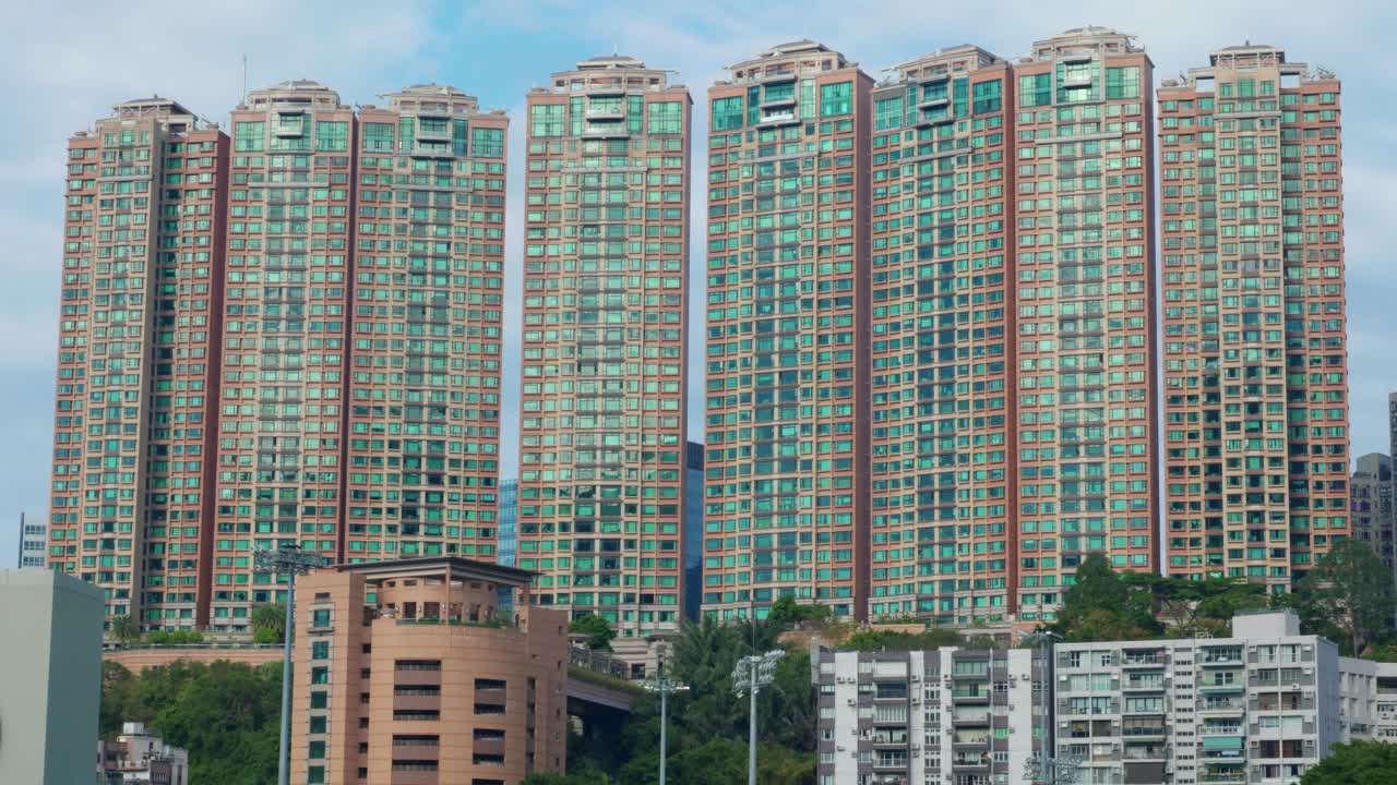 Vista panorâmica de edifícios de apartamentos e arranha-céus no centro de Hong Kong, China, em um dia ensolarado, mostrando a densidade da vida urbana e a arquitetura moderna.