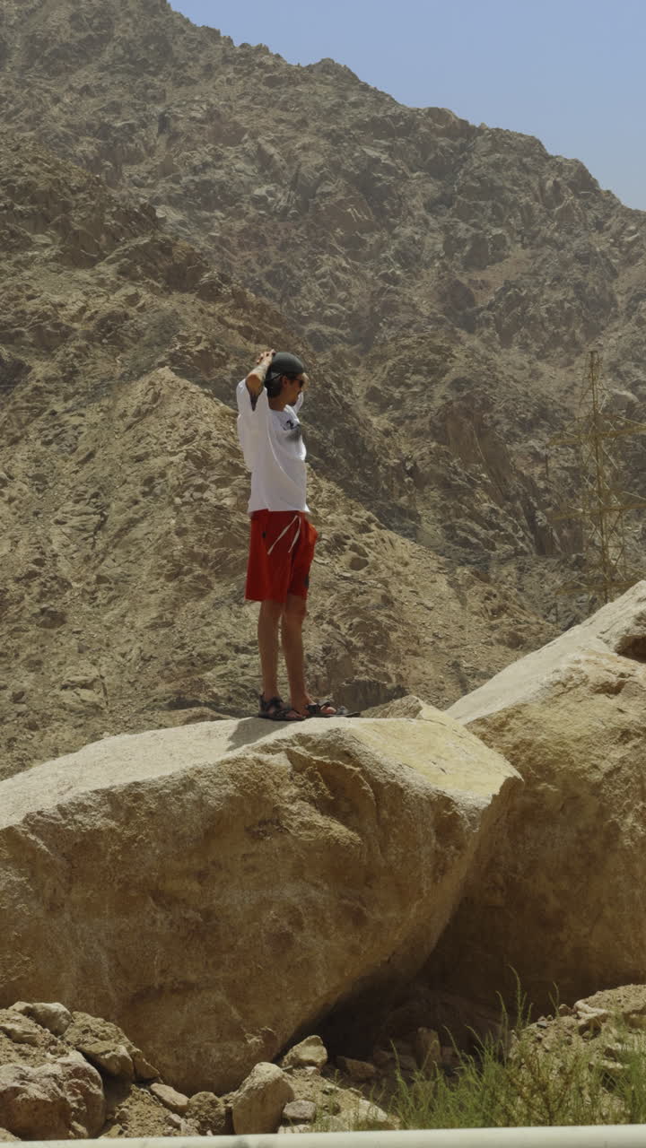 hombre de pie en una roca en un paisaje desértico montañoso