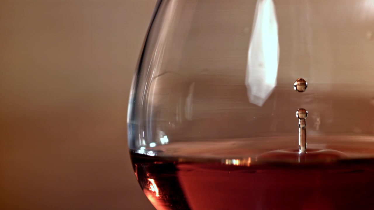 Nahaufnahme eines Tropfens, der in Zeitlupe in Rotwein fällt