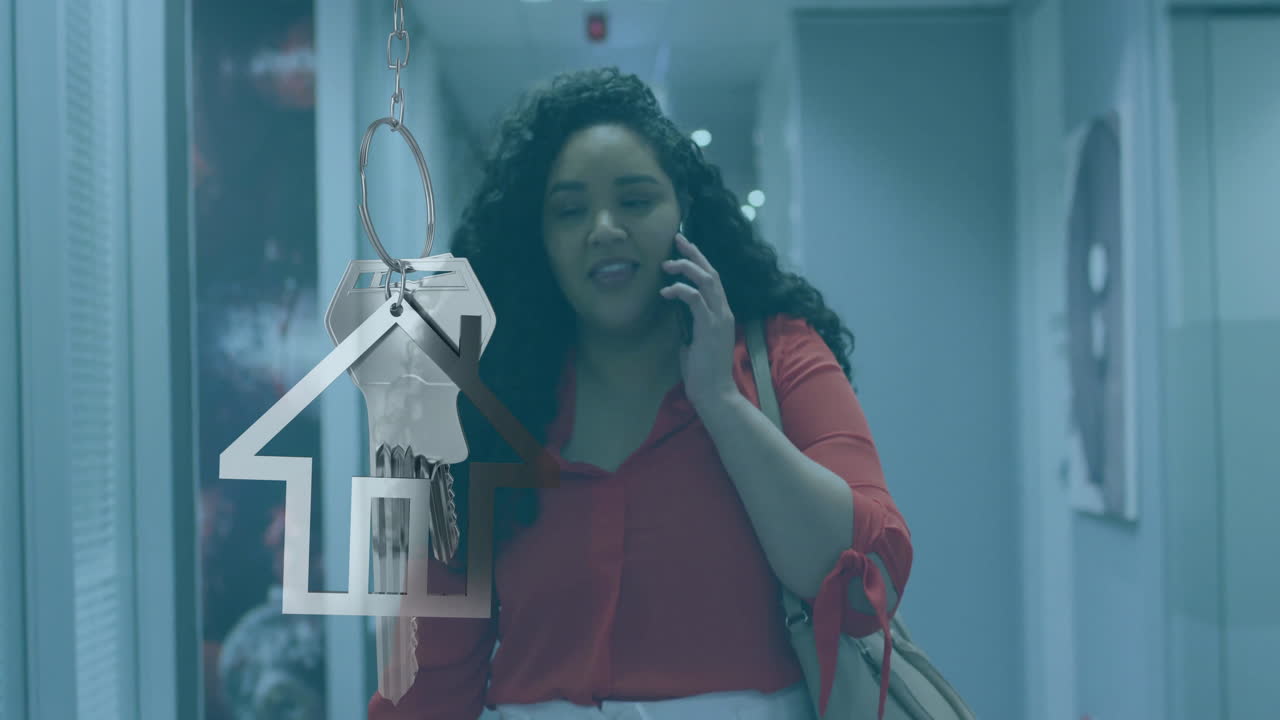 animación de casa y llave sobre mujer de negocios biracial hablando en teléfono inteligente en la oficina