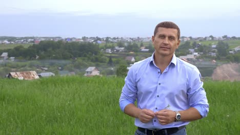 man standing in a field overlooking a river and village