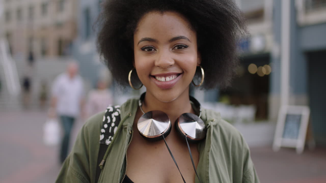 retrato en cámara lenta de una joven afroamericana de moda que usa una aplicación de teléfono inteligente, envía mensajes de texto, navega por las redes sociales y disfruta del estilo de vida urbano