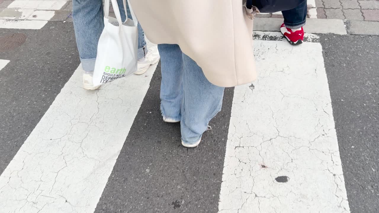 Pejalan kaki dengan pakaian kasual melintasi penyeberangan zebra kota di siang hari di Tokyo