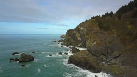 Aerial-drone-of-Northern-California-coastal-cliffs-and-crashing-waves-with-evergreens