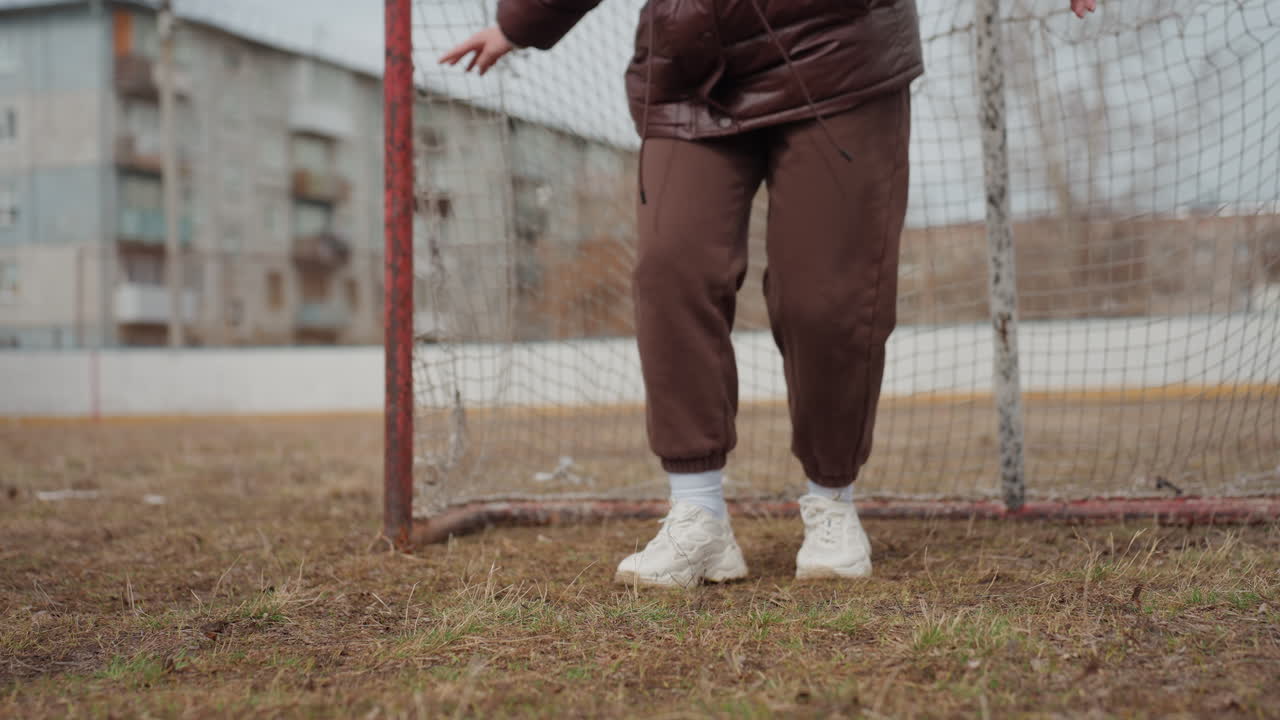 El portero ajusta rápidamente su postura en respuesta a las desafiantes condiciones del partido; los porteros atentos ejecutan movimientos laterales rápidos para mantener una posición óptima en superficies irregulares.