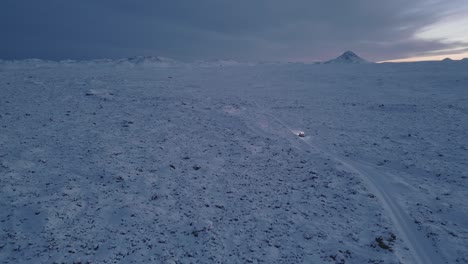 Jeep-driving-through-snowy-highland-road-in-middle-of-nowhere,-Iceland