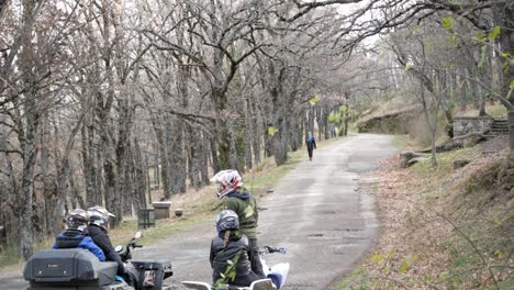 un par de quads con dos personas cada uno están detenidos al pie de una colina en el bosque