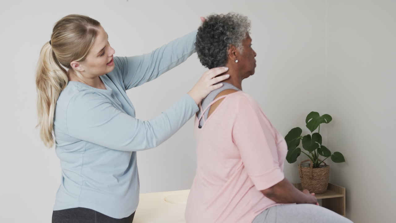 fisioterapeuta caucásica chequeando el cuello de una mujer mayor, espacio de copia, cámara lenta