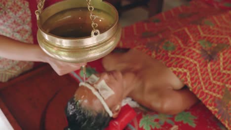 High-angle-view-of-a-woman-receiving-a-stress-relieving-Shirodhara-treatment-during-an-Ayurvedic-vacation-retreat