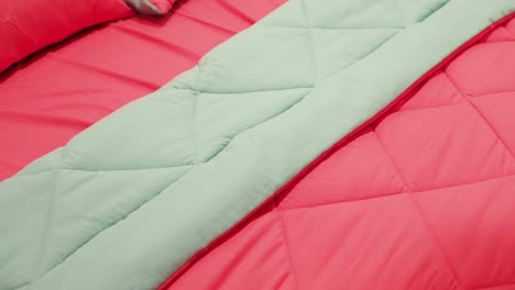 close up of a pink and mint green bedspread