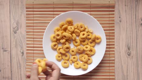 hand picking ring cereal from a plate