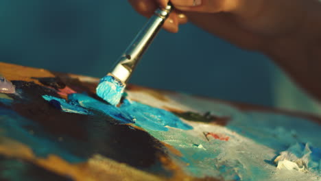 Hands-of-female-artist-holding-dirty-palette-with-different-paints