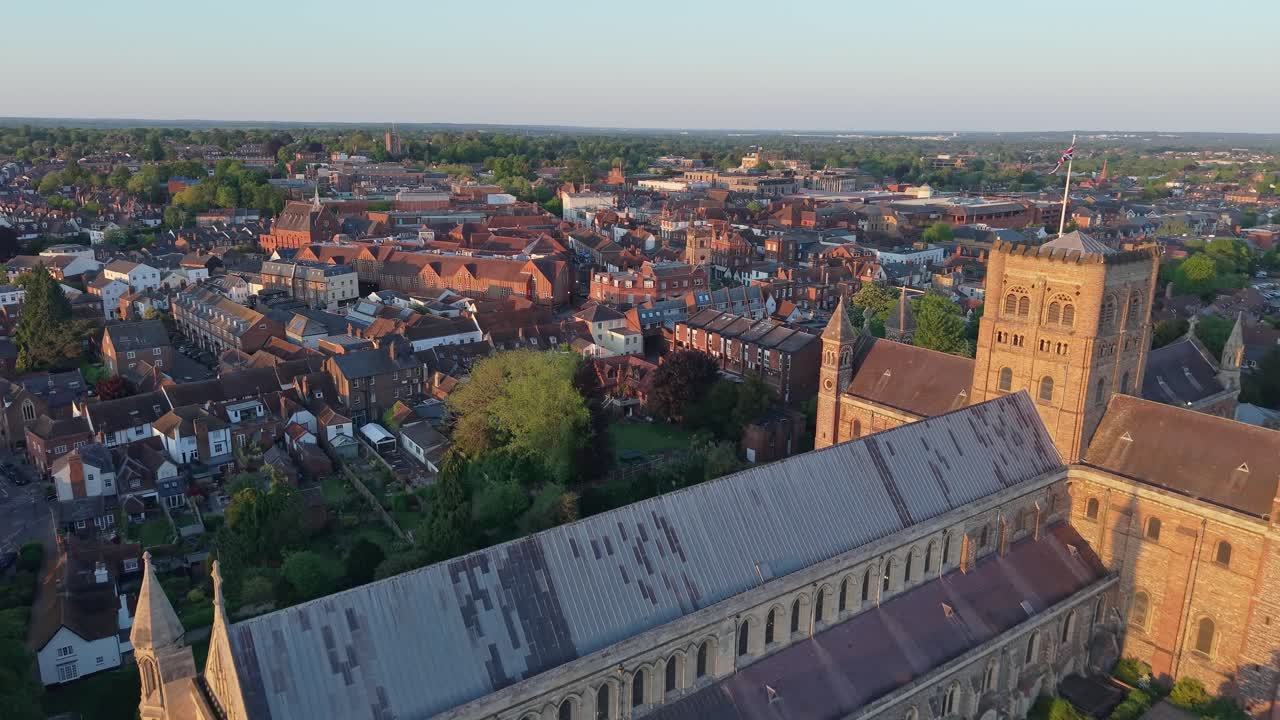 A cinematic drone pullback reveals St Albans Cathedral glowing in the warm sunset light, highlighting its stunning gothic architecture and historic beauty