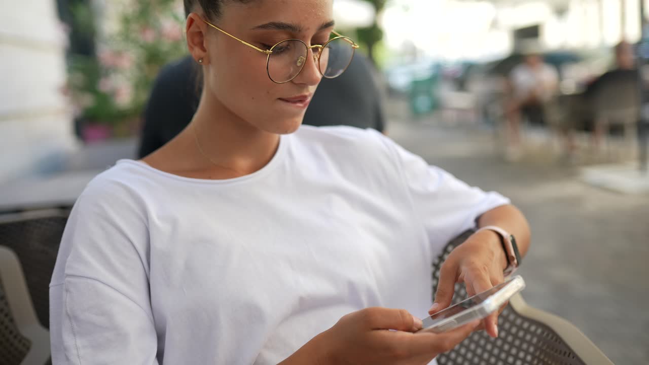 joven usando el teléfono en un café al aire libre