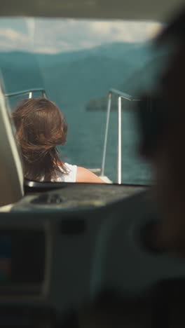 woman takes sunbathe on deck while skipper drives yacht in calm sea. lady enjoys motorboat trip with skilled captain on tropical vacation. boat cruise