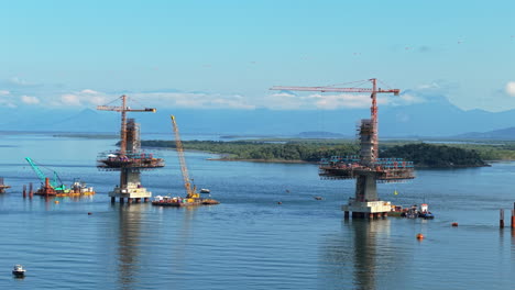 cranes lifting bridge sections during construction of ponte de guaratuba-matinhos in brazil