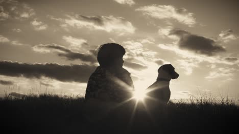 4k outdoor silhouette of child and dog watching the sunset