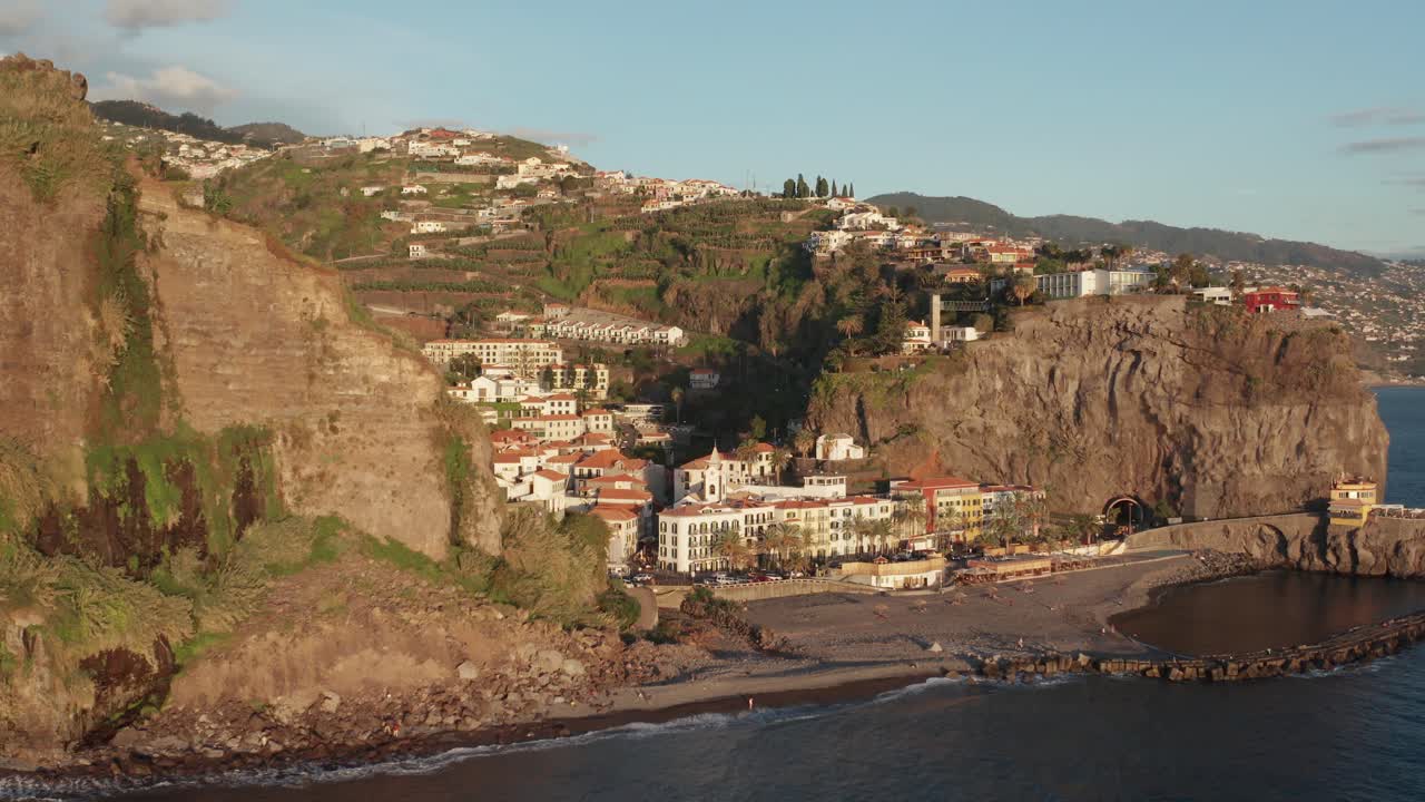 Città costiera calma e serena sull'oceano che si rivela lentamente dietro la montagna durante il tramonto a Ponta Do Sol, Madeira, Portogallo