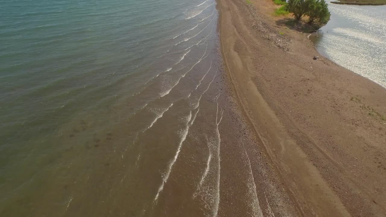 аэрофотоснимок: дельта реки с проходящим через нее автомобильным мостом и некоторыми сельскохозяйственными постройками