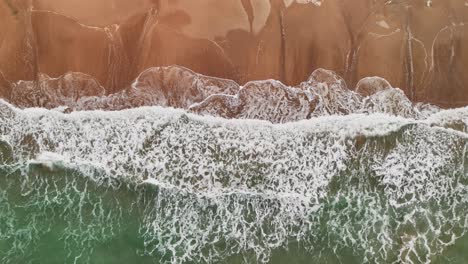 birdseye aerial footage of waves crashing on a thai beach