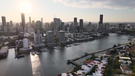 brisbane, australia. drone pull back over the river, residential area with promenade in the evening.