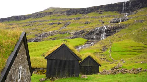 establishing pan shot of saksun village with grass turf houses roofs, faroe