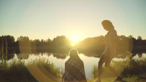 young people enjoy rest by river during sunset. girls with guy meet dawn