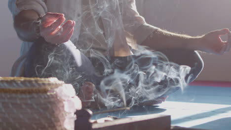 Man-sitting-in-lotus-pose-with-smoke-from-incense-around-him