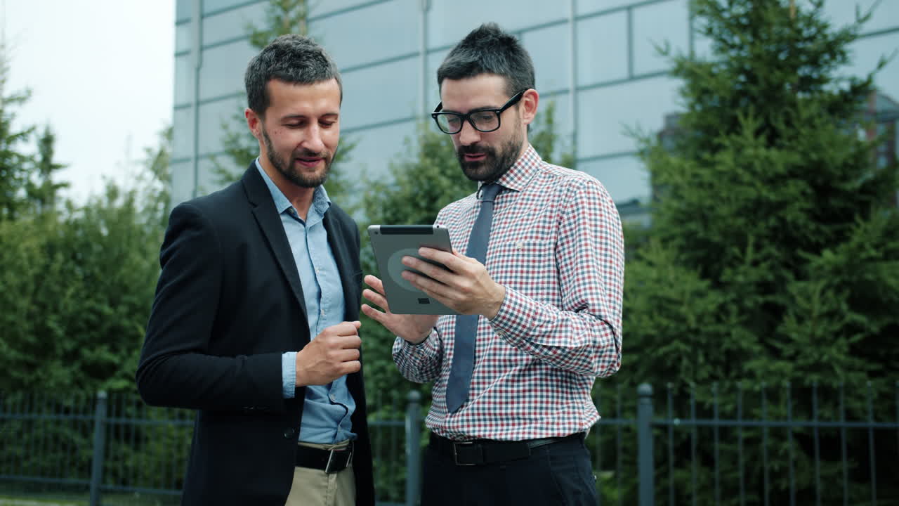 Businessmen Discussing on a Tablet Outside a Building